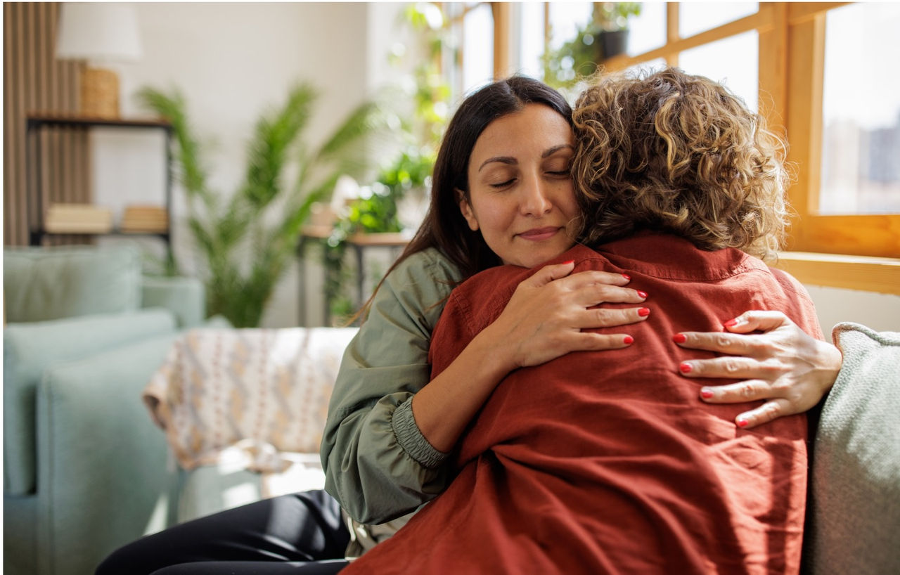two women hugging on couch